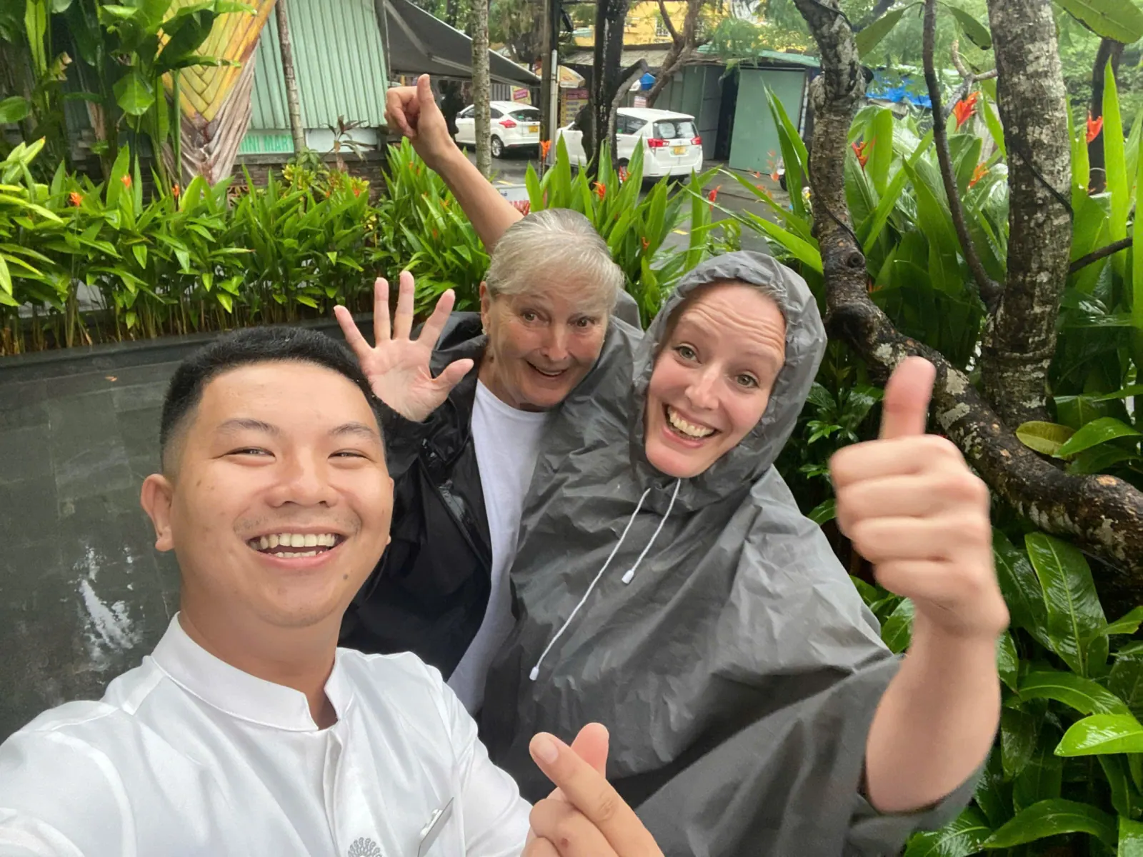 Tom and two guests in rain ponchos giving a thumbs up on a wet-season tour