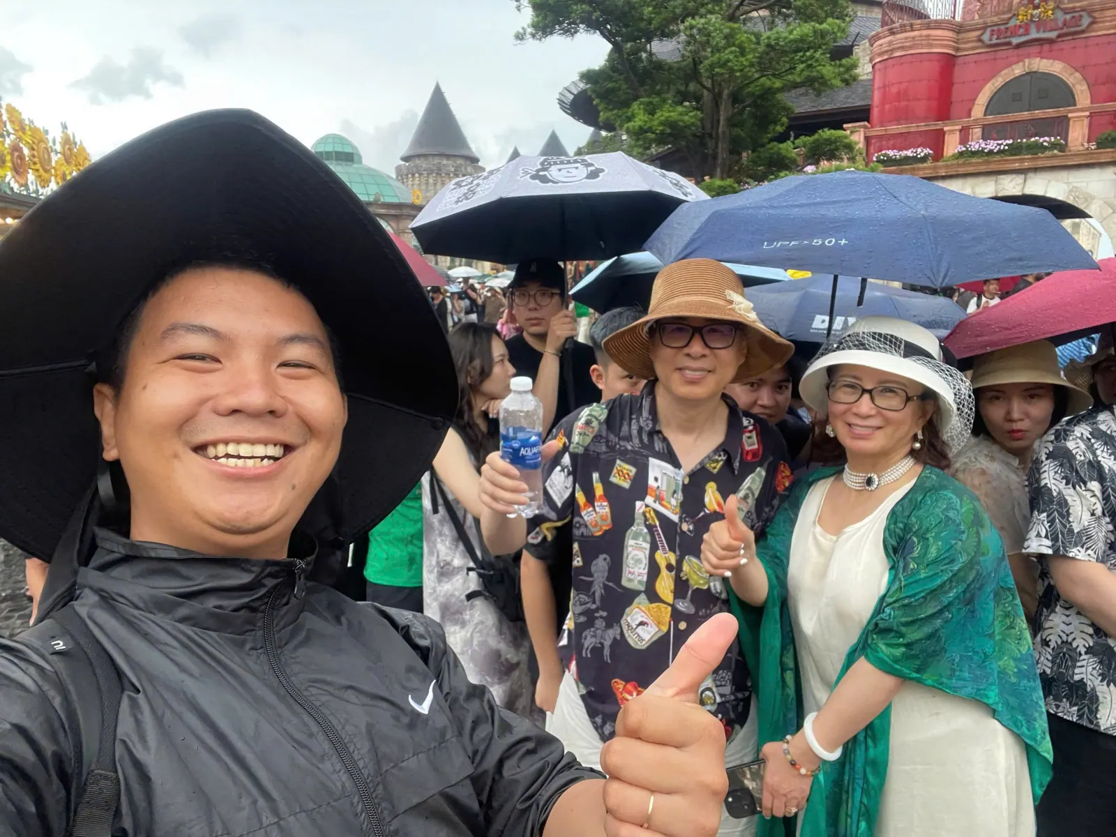 Tom with guests sheltering under umbrellas on a rainy day at Ba Na Hills