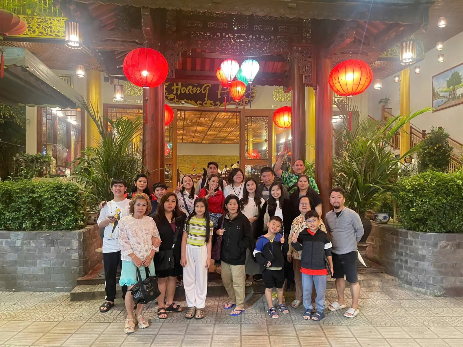 A family group outside a Hoi An restaurant hung with red lanterns at the end of a tour