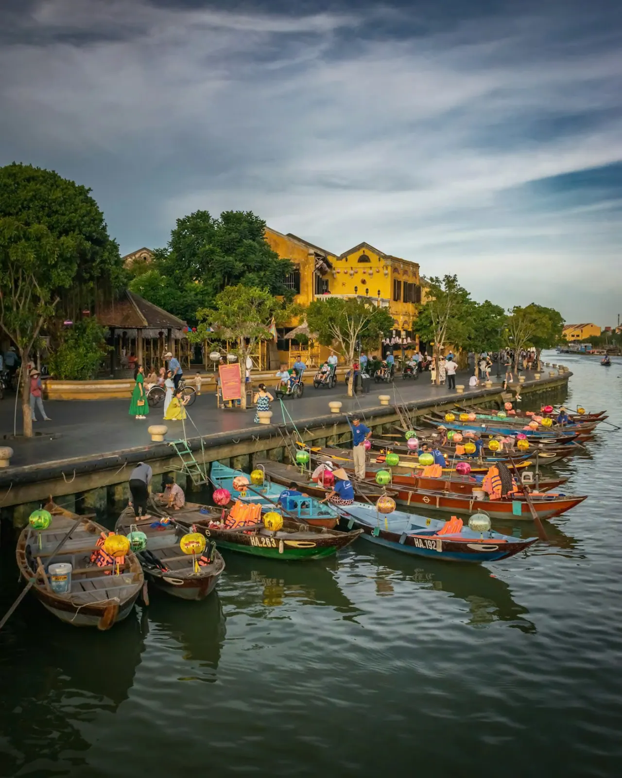 Hoi An Ancient Town at dusk, with the yellow riverfront houses and boats moored on the Thu Bon