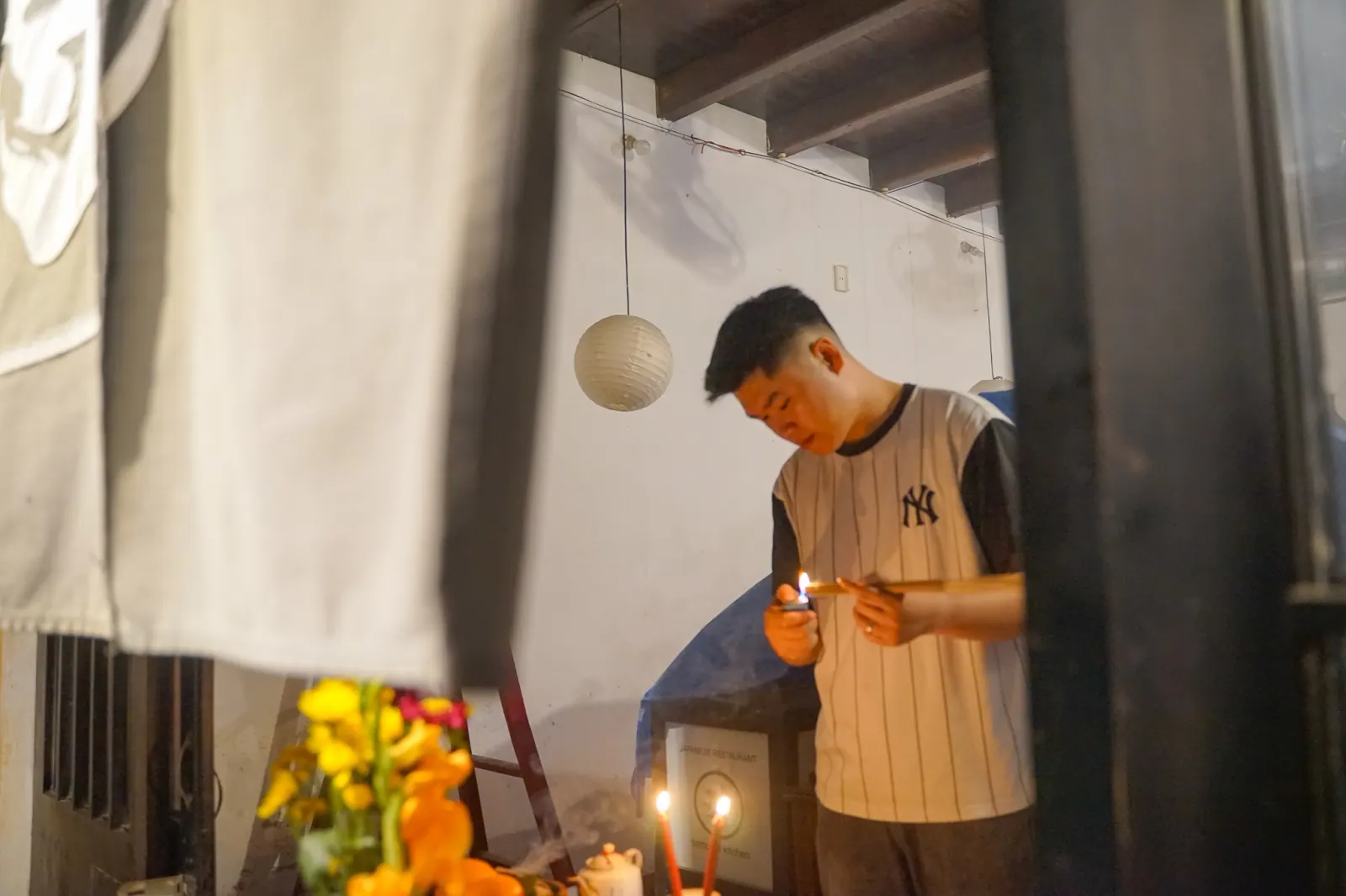 Young man lighting a candle at the family altar before the midnight incense on Tet eve