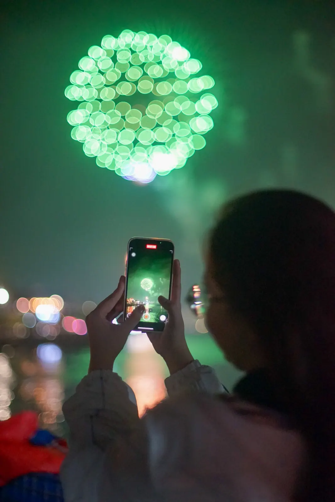 Someone filming the green Tet fireworks on a phone above the Thu Bon river
