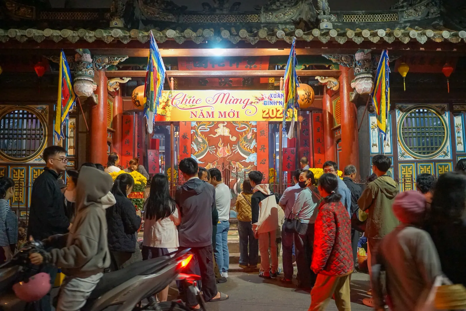 Crowd gathering at a Hoi An temple gate under a “Chuc Mung Nam Moi 2026” banner just after midnight