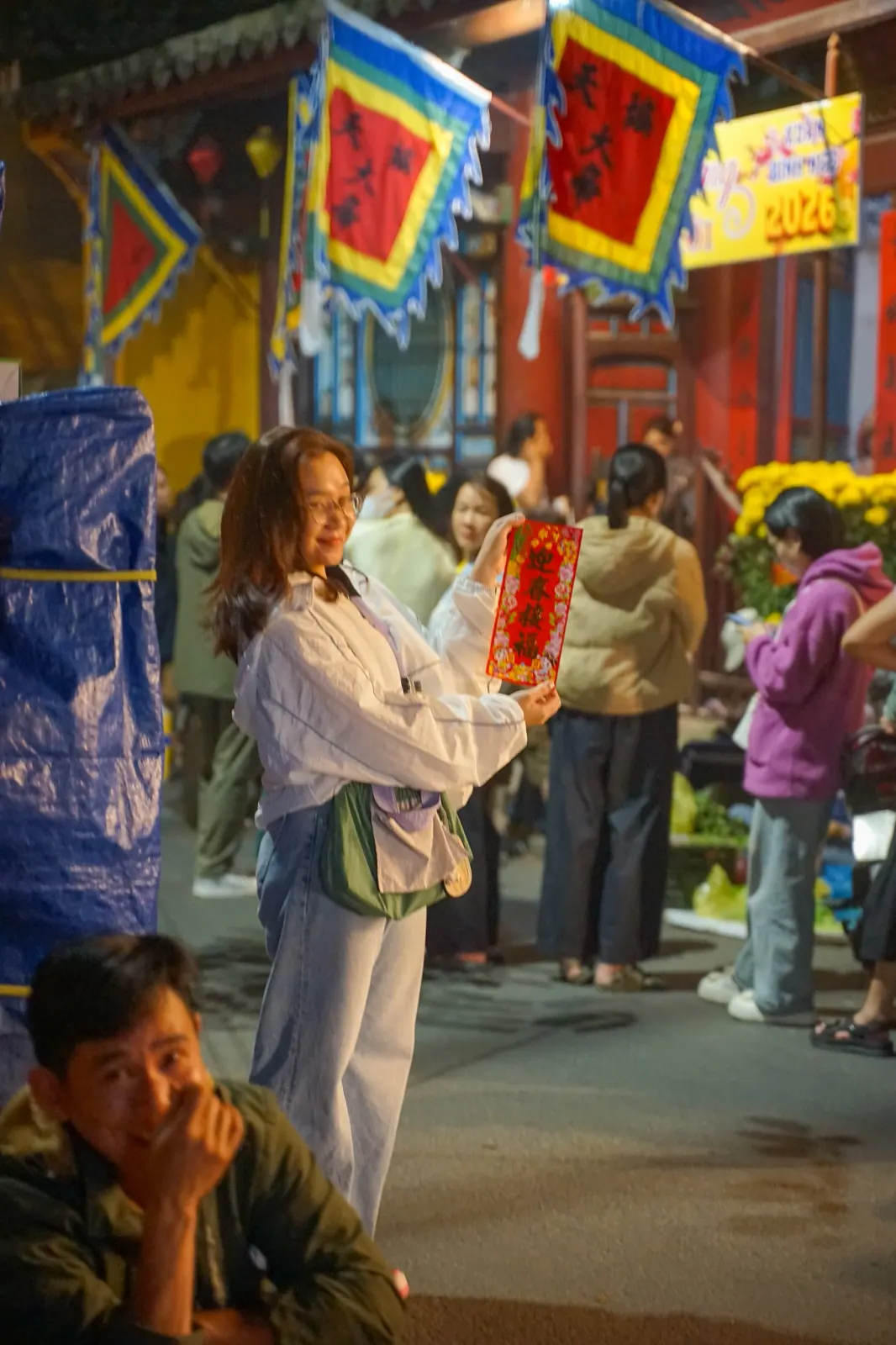 Traveller smiling with her fortune slip in the temple courtyard on the first morning of Tet