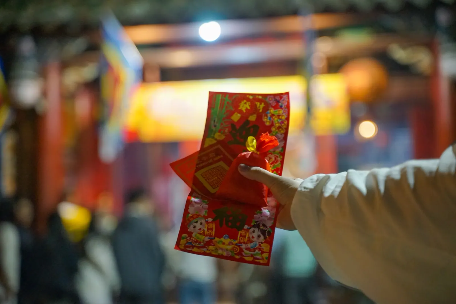 Holding up a small red lucky packet taken from the temple after midnight